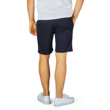 A person standing in a white t-shirt, Berwich navy blue cotton stretch Bermuda shorts, and white sneakers against a light background.