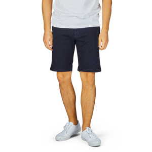 Man wearing Berwich navy blue cotton stretch Bermuda shorts and white sneakers standing against a light background, ready for summer vacation.