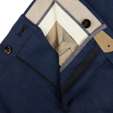 Close-up of a folded blue Berwich men's dress shirt with a price tag, showcasing its collar, button, and inner lining details alongside Navy Blue Melange Linen Flat Front Trousers.