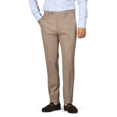 A person wearing Berwich's Oatmeal Melange Wool Flannel Flat Front Trousers, paired with a light blue shirt and brown loafers, stands casually with hands in pockets.