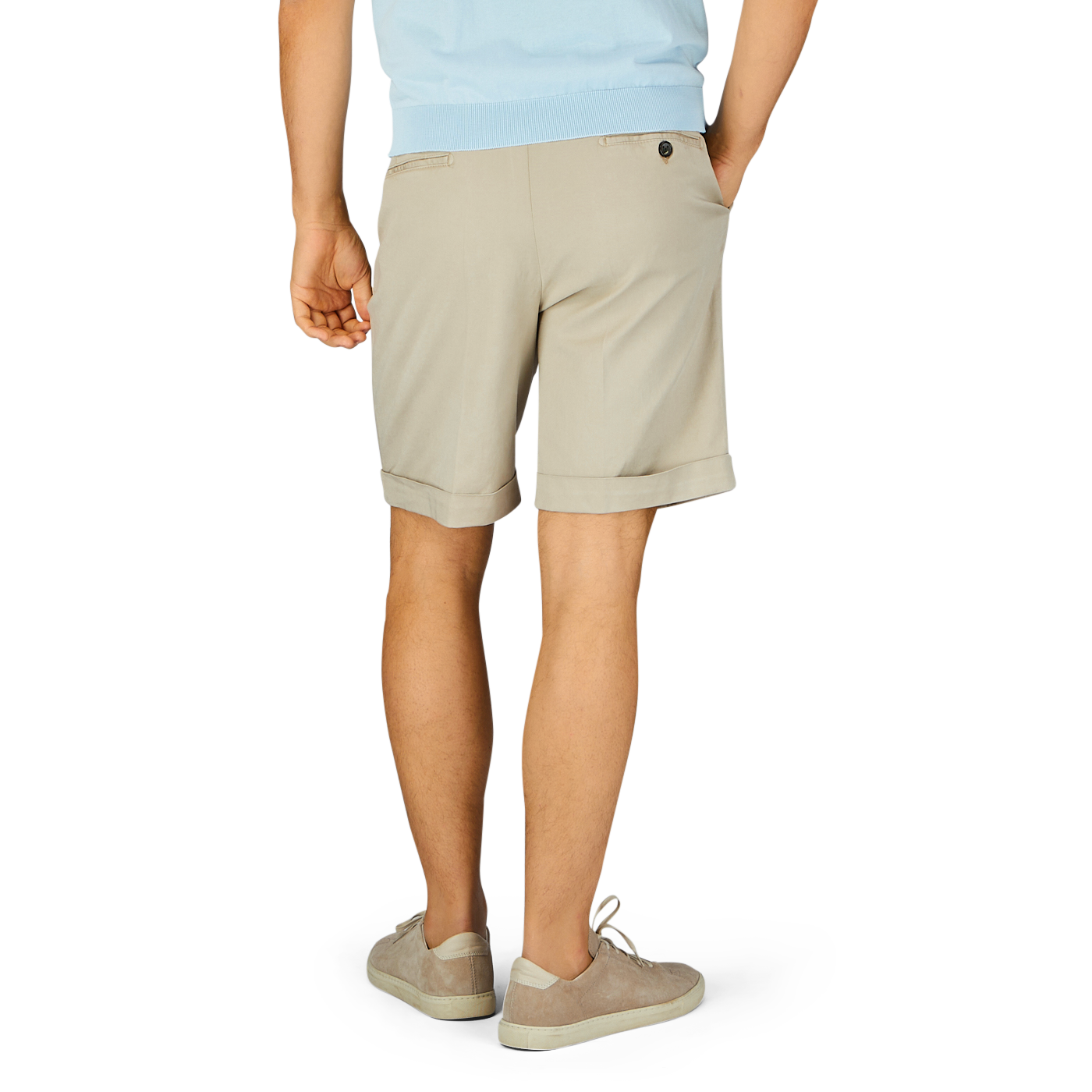 Man standing in Sabbia Beige Cotton Blend Pleated Shorts by Berwich and light-colored sneakers against a blue background.