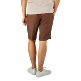 A man wearing a light beige T-shirt and Berwich's Terra Brown Washed Linen Drawstring Shorts, standing with white sneakers on a plain background.