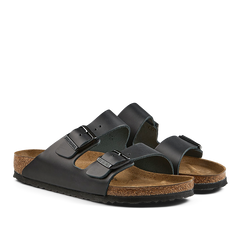 A pair of Black Natural Leather Arizona Sandals with cork soles by Birkenstock.