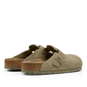 A pair of faded khaki suede leather Birkenstock Boston slippers with buckle straps and cork soles displayed against a neutral background.