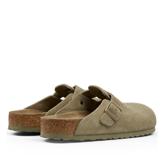 A pair of faded khaki suede leather Birkenstock Boston slippers with buckle straps and cork soles displayed against a neutral background.