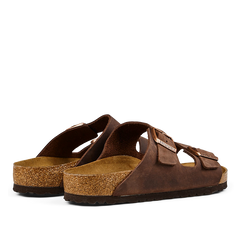 A pair of brown leather Birkenstock Arizona sandals with cork footbeds and rubber soles.