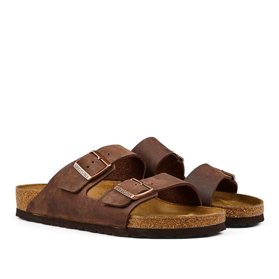 A pair of brown, Birkenstock Habana Brown Natural Leather Arizona sandals with adjustable leather straps and a cork footbed.