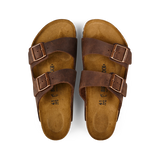 A pair of Habana Brown Natural Leather Birkenstock Arizona sandals with adjustable straps and cork footbeds, displayed on a black background.