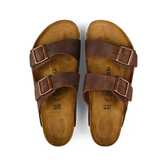 A pair of Habana Brown Natural Leather Birkenstock Arizona sandals with adjustable straps and cork footbeds, displayed on a black background.