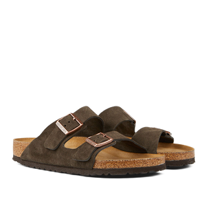 A pair of mocha brown suede leather Birkenstock Arizona sandals with cork soles on a transparent background.