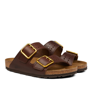 A pair of Birkenstock Roast Bold Natural Leather Arizona Sandals featuring two adjustable leather straps with gold buckles and a cork, anatomically-supported footbed.