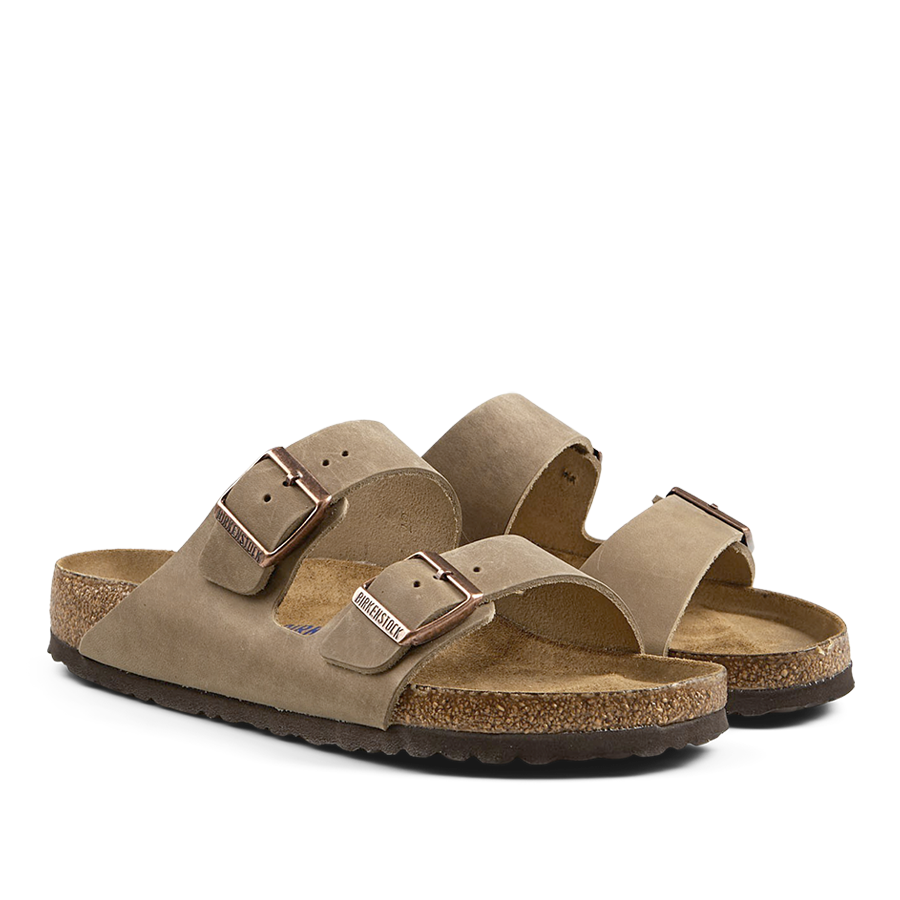 A pair of suede, open-toe Birkenstock sandals with buckle straps and cork soles.