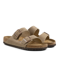 A pair of suede, open-toe Birkenstock sandals with buckle straps and cork soles.