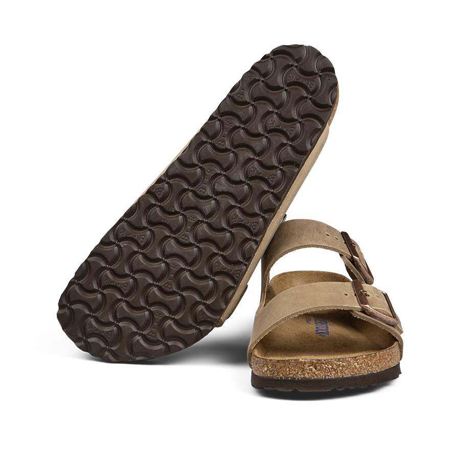 A pair of Birkenstock Tabacco Brown Natural Leather Arizona sandals with one flipped showing the sole.