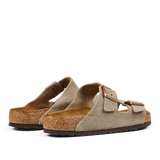A pair of taupe beige suede leather Birkenstock Arizona sandals with adjustable straps and cork soles.