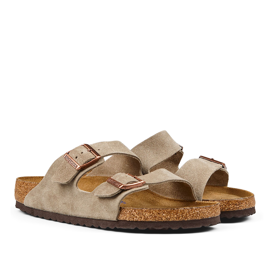 A pair of taupe beige suede leather Birkenstock Arizona sandals with cork footbeds and rubber soles.