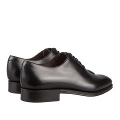 Introducing the Carmina Black Calf Leather Wholecut Rain Oxford Shoes – a pair of sleek black oxfords, meticulously crafted from premium calf leather and showcasing Goodyear welted construction. These lace-up shoes are elegantly presented at a slight angle, highlighting both their front and back views.