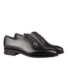 A pair of Carmina Black Calf Leather Wholecut Rain Oxford Shoes featuring closed lacing, a smooth finish, and low heels.