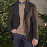 A man, wearing a Boglioli Brown Checked Lambswool K Jacket, stands confidently in front of a beautifully decorated Christmas tree, showcasing the impeccable unstructured craftsmanship of his attire.