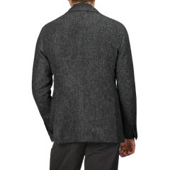 A person wearing a dark grey herringbone wool tweed jacket with long sleeves from Boglioli is viewed from the back against a plain background, highlighting the unstructured craftsmanship of the K Jacket.