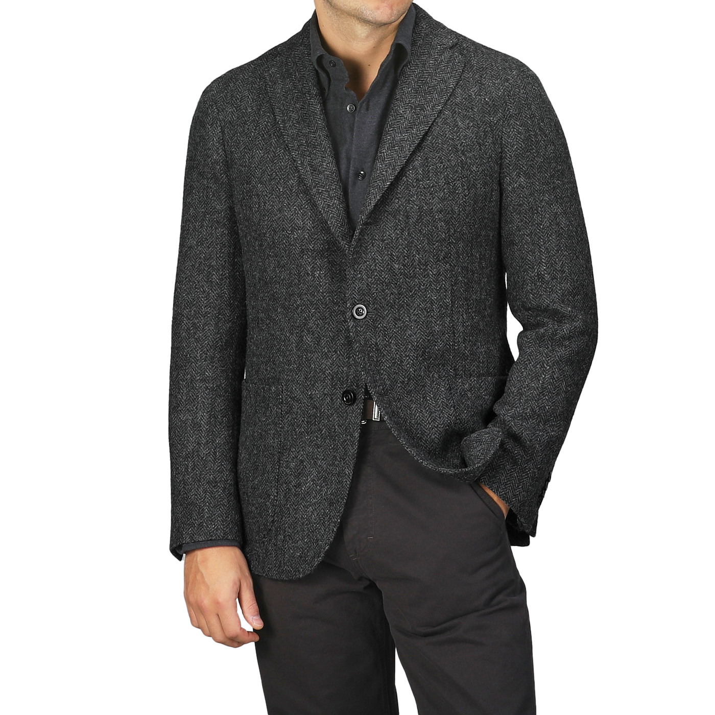 A person wearing a Boglioli Dark Grey Herringbone Wool Tweed K Jacket, featuring unstructured craftsmanship, over a button-up shirt, with one hand in their pants pocket.