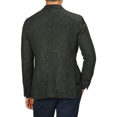 A person wearing a green herringbone wool tweed K Jacket by Boglioli and navy pants, showcasing unstructured craftsmanship, photographed from the back.