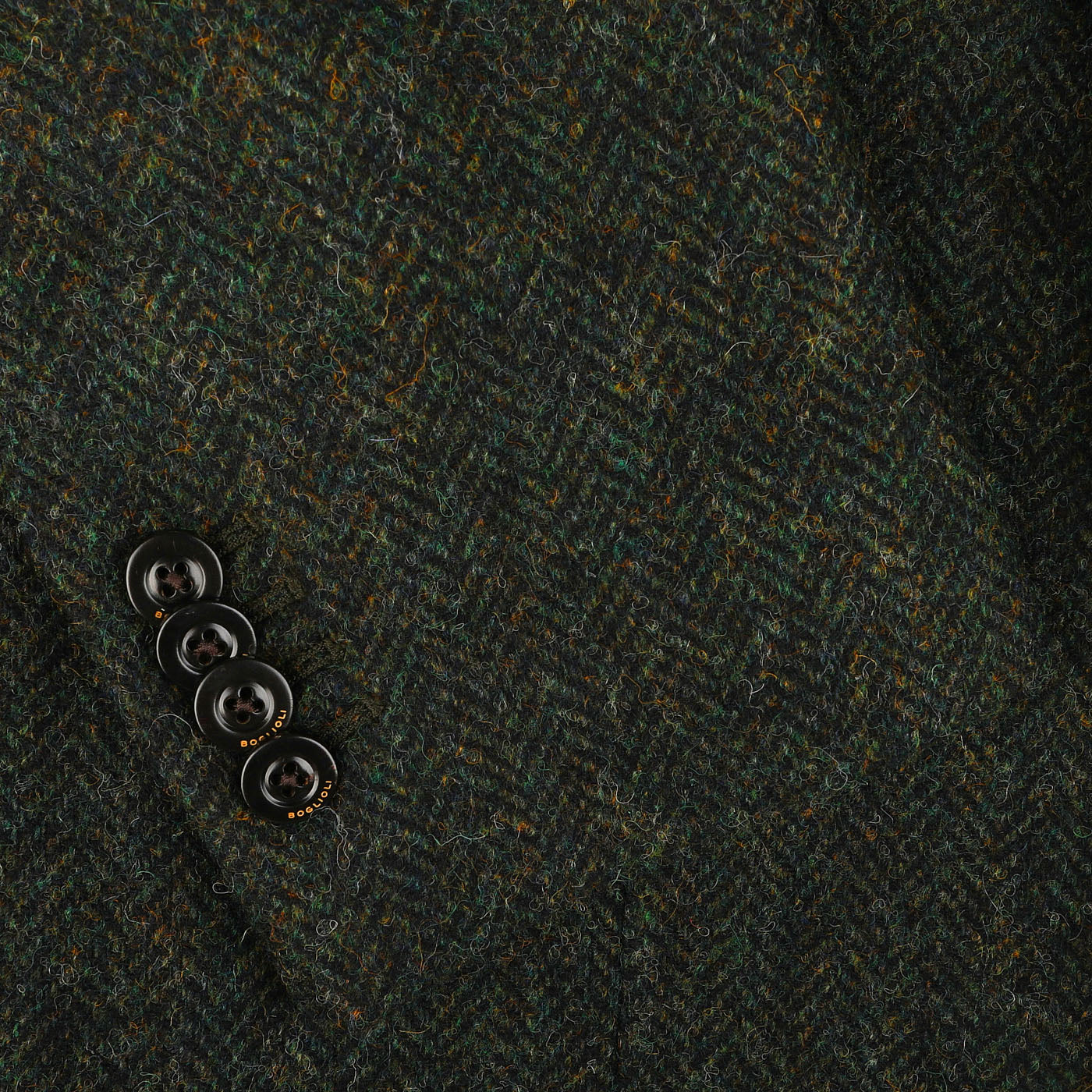 Close-up of a Boglioli Green Herringbone Wool Tweed K Jacket, featuring unstructured craftsmanship and four black buttons on the sleeve.