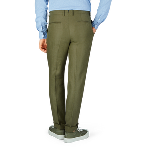 A person standing in Boglioli green washed Irish linen trousers and gray sneakers paired with a light blue shirt.