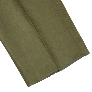 Olive green linen fabric with a clean-cut edge and frayed corner against a white background.