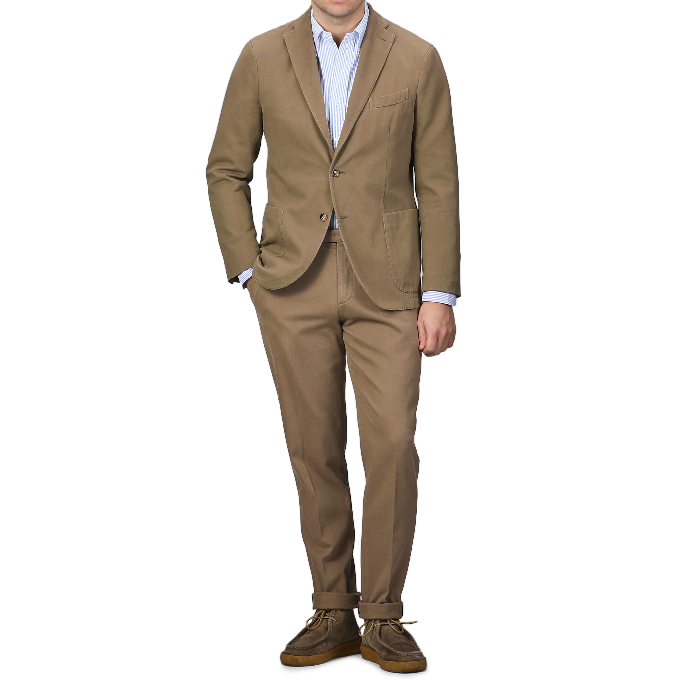 A person dons a Boglioli Khaki Beige Heavy Cotton Twill Suit, expertly paired with a light blue shirt and brown shoes, exuding confidence against a plain background.