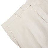 Close-up of a light beige Boglioli linen trouser waistband with a belt loop on a white background.
