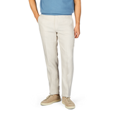 A person wearing light beige washed Irish linen Boglioli trousers paired with a blue t-shirt and beige shoes, cropped at the waist.