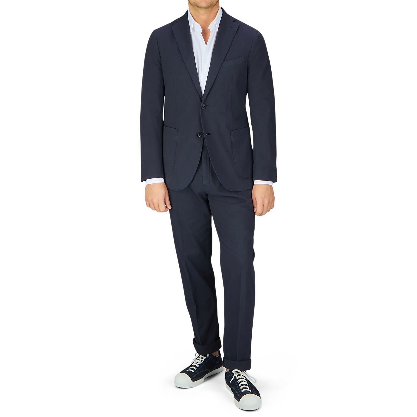 Man in a navy blue Boglioli Navy Blue Washed Cotton K Jacket crafted with unstructured craftsmanship from Italy, paired with a white shirt and casual sneakers standing against a white background.