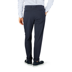 A man's legs in Boglioli navy blue washed cotton pleated trousers and hands in the back.