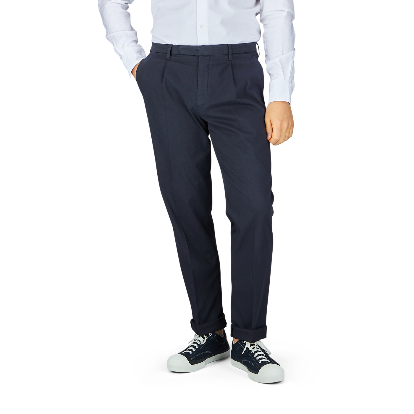 A person standing wearing Boglioli navy blue washed cotton pleated trousers and a white shirt with black and white sneakers.
