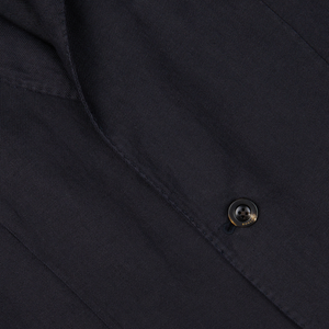 Close-up of a black button on a Boglioli Navy Blue Washed Irish Linen K Jacket fabric.