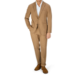 A man wearing a tan Boglioli Tobacco Brown Washed Cotton K Jacket and brown shoes stands against a light-colored background.