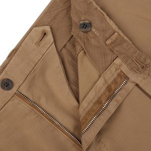 Close-up of Boglioli Tobacco Brown Washed Cotton Pleated Trousers with a zipper and button detail.