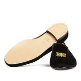 A single Black Velvet American Eagle slipper from Bowhill Elliott with a gold embroidered emblem on the upper, displayed against a translucent striped background.