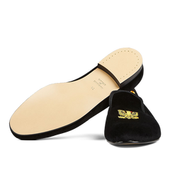 A single Black Velvet American Eagle slipper from Bowhill Elliott with a gold embroidered emblem on the upper, displayed against a translucent striped background.