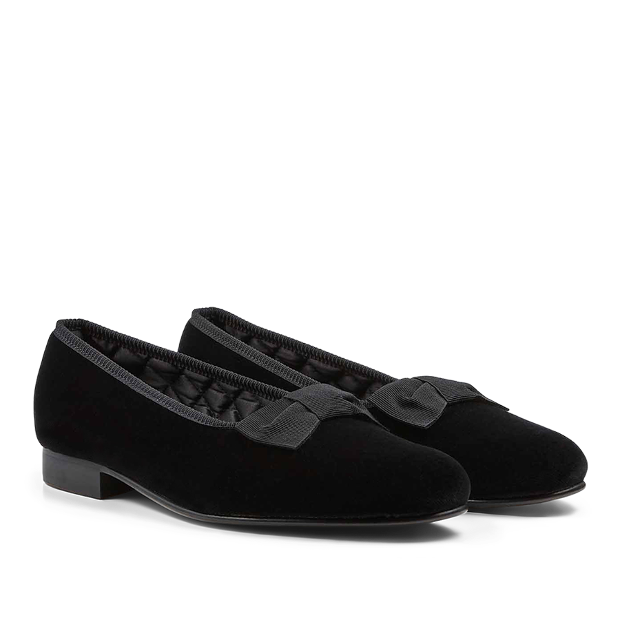 A pair of Black Velvet Bow Opera Pumps by Bowhill Elliott women's formal shoes with bows on a black background.