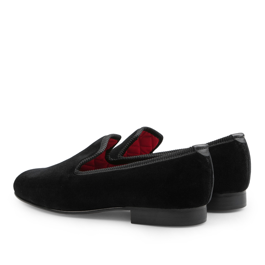 The Plain Black Velvet Albert Slippers by Bowhill Elliott are crafted with a luxurious red quilted inner lining, a thick sole, and a low heel.