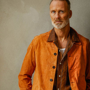 A man in a slim fit Manto Bright Tan Suede Leather Overshirt leaning against a wall.