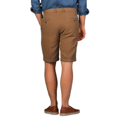 Rear view of a person wearing a blue shirt and Briglia's Camel Brown Cotton Linen Drawstring Malibu Shorts paired with matching shoes.