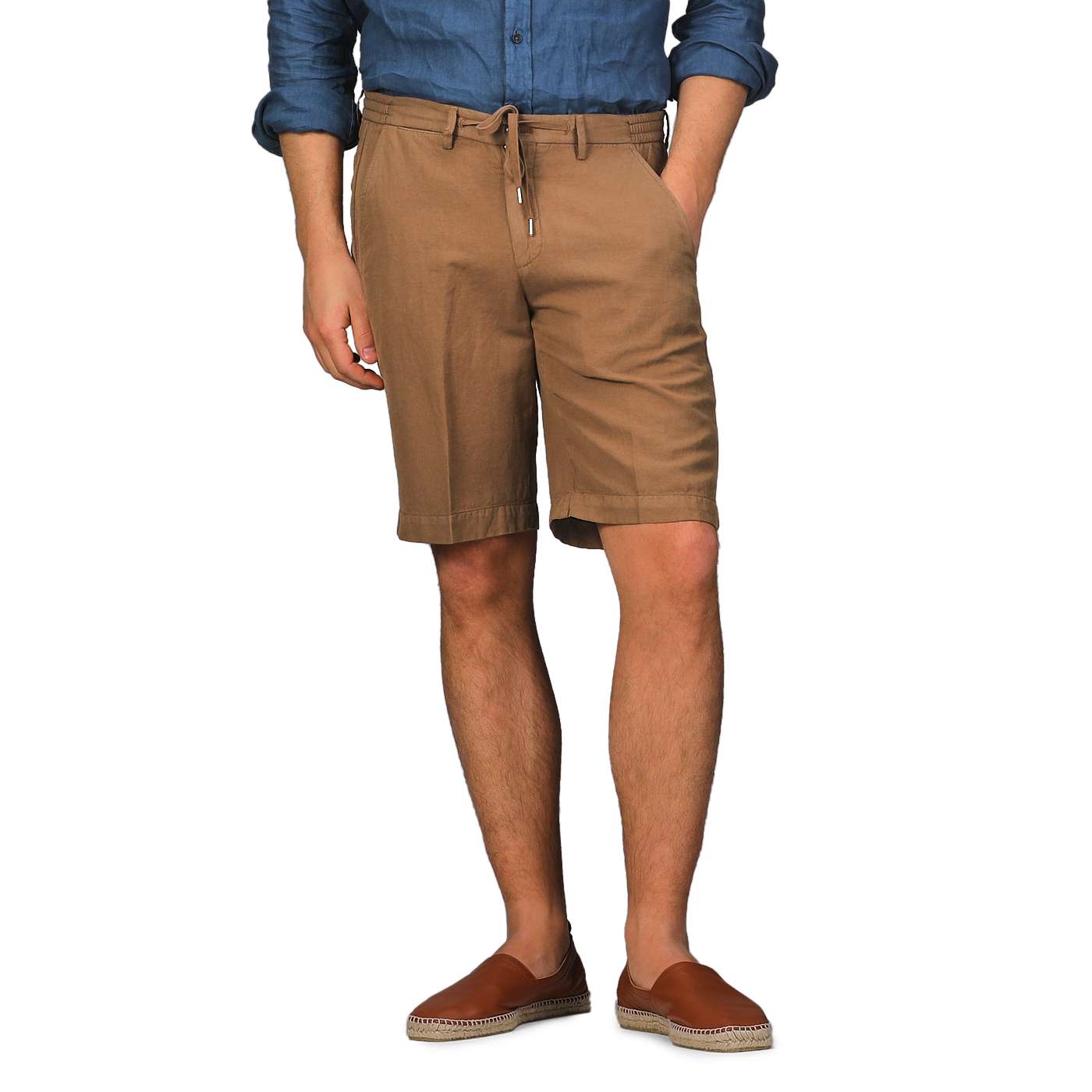 A person in a blue shirt, Camel Brown Cotton Linen Drawstring Malibu Shorts by Briglia, and brown loafers stands against a gray background.