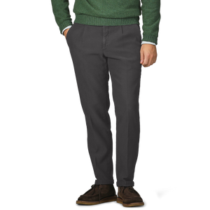 A person wearing a green sweater and Briglia's Dark Grey Cotton Twill BG21 Pleated Trousers, hands in pockets, with brown shoes visible.