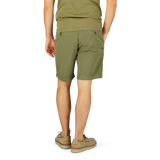 Person standing in Briglia grass green cotton linen pleated shorts and beige sandals against a white background.