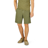 Man wearing Briglia's grass green cotton linen pleated shorts with an adjustable waistband and tan shoes standing against a neutral background.