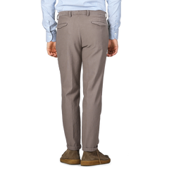 Rear view of a person wearing a blue pinstriped shirt, Briglia's Mole Brown Cotton Twill BG21 Pleated Trousers, and brown shoes standing against a plain background.