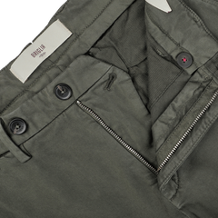 Close-up of an open zipper and button fastening on a pair of slim fit, moss green BG62 trousers. The waistband label reads "Briglia," showcasing the fine craftsmanship in cotton stretch fabric.